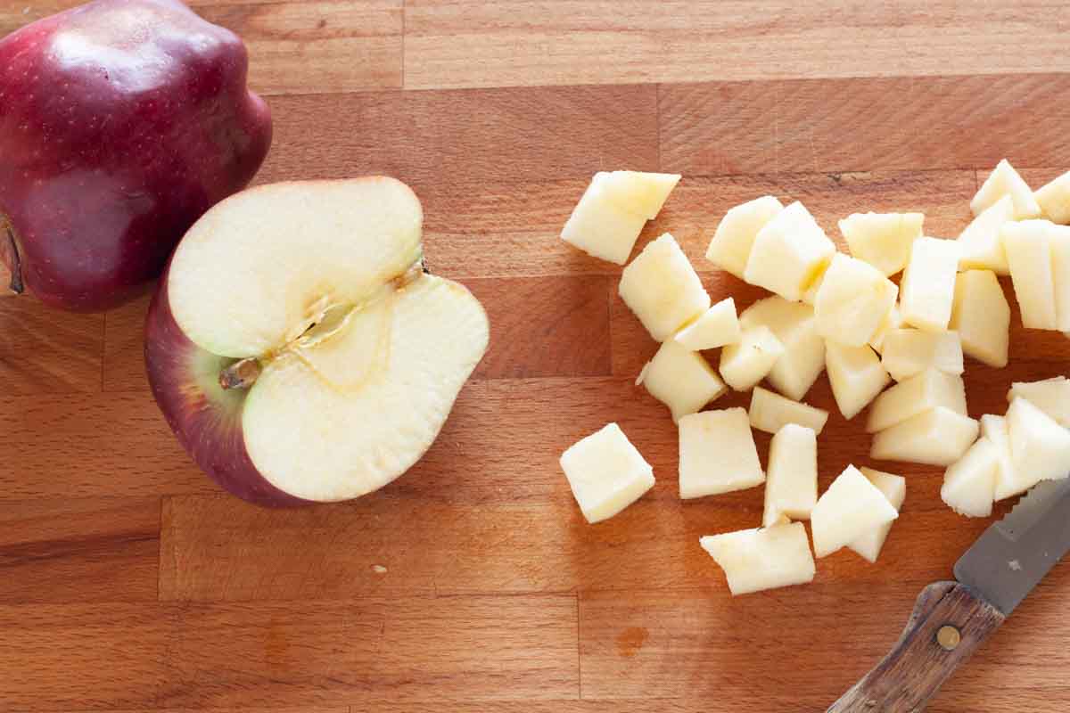 Cutting apples into chunks on a wooden cutting board.