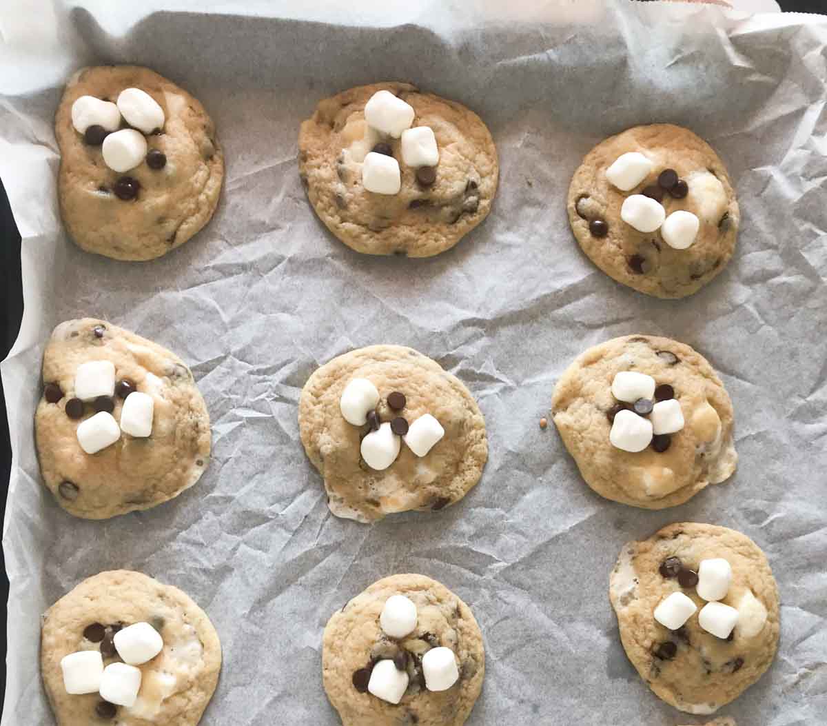 Adding mini marshmallows and chocolate chips on cookies.
