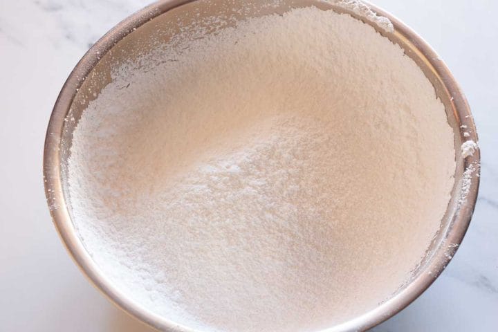 Sifted powdered sugar in a metal mixing bowl.
