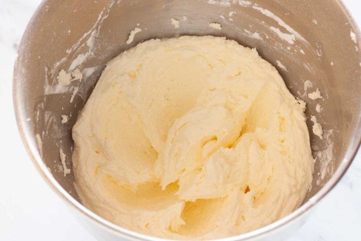 Creamed butter mixed with powdered sugar in the bowl of a stand mixer.