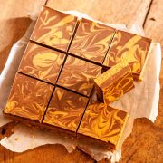 Chocolate peanut butter oatmeal bars cut into nine large squares on parchment paper on a wooden surface.