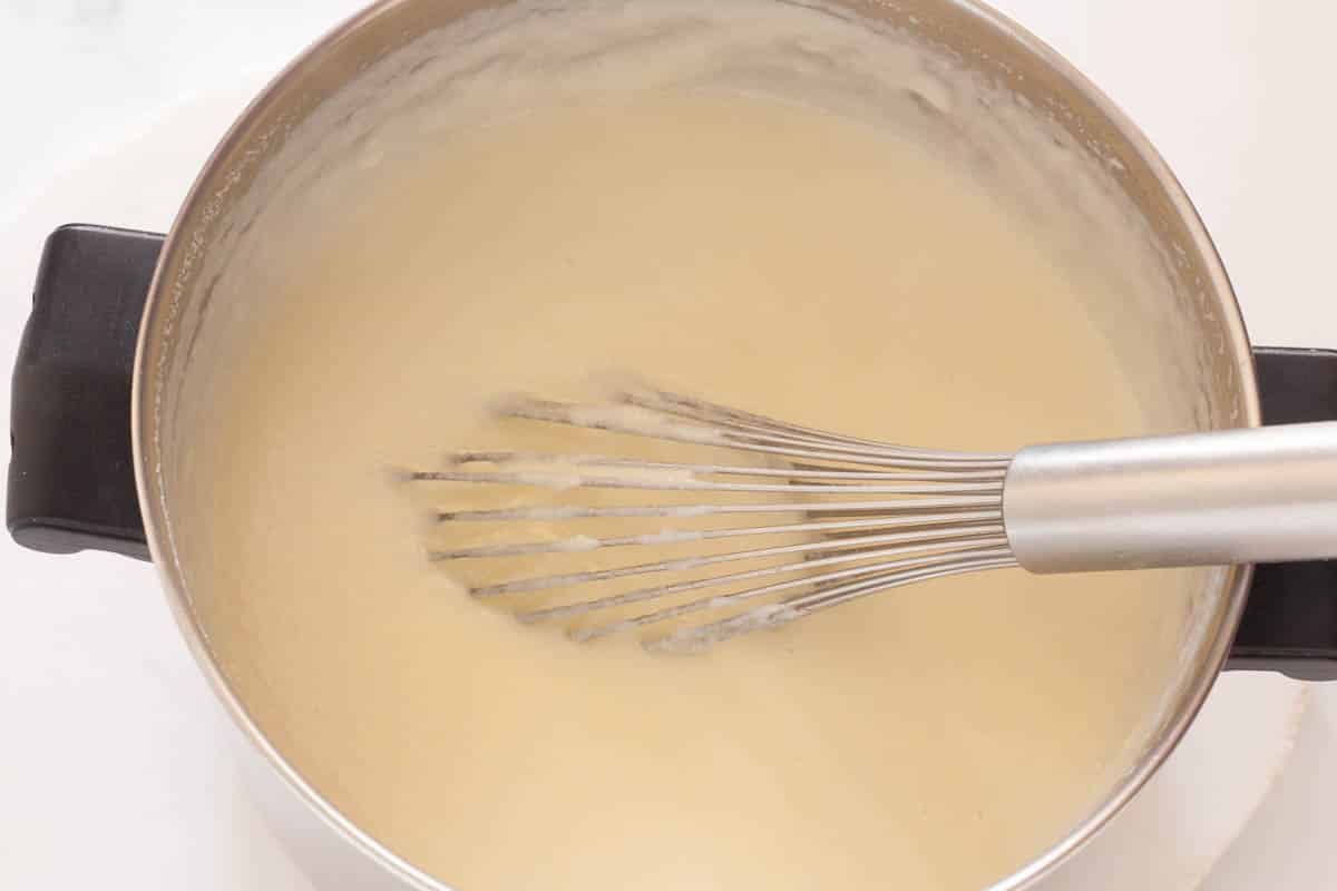 A saucepan full of bougatsa cream custard with a whisk.