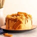 Lotus Biscoff cake next to a white vase filled with wheat sheaves.