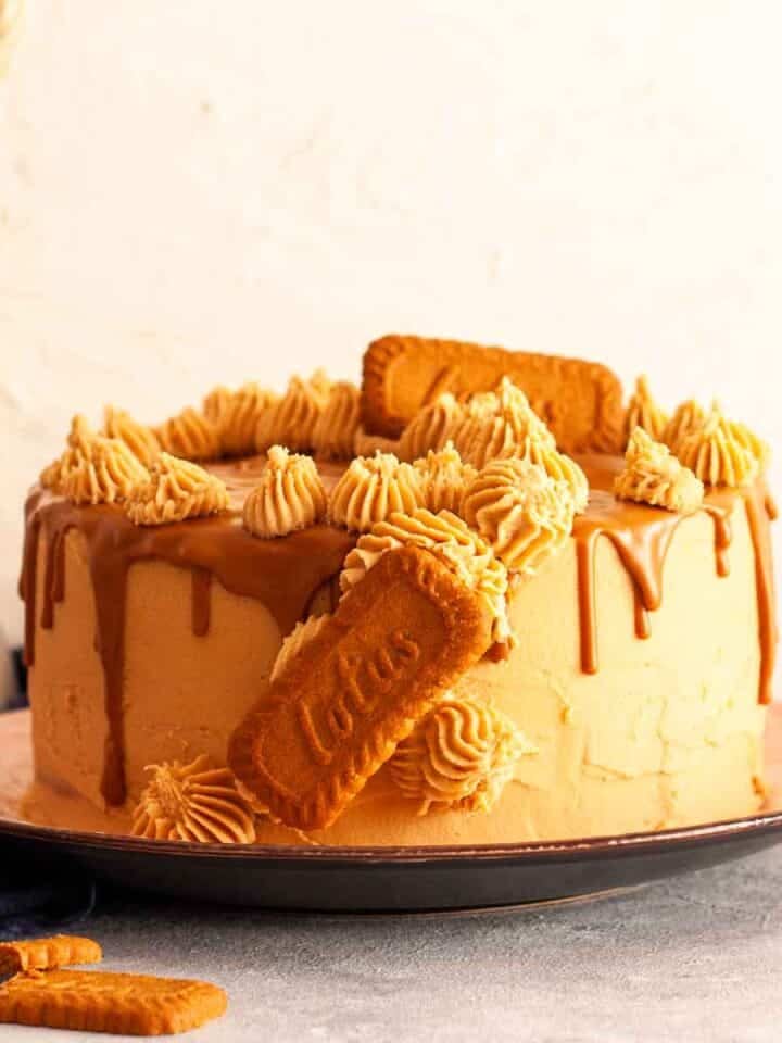 Lotus Biscoff cake next to a white vase filled with wheat sheaves.