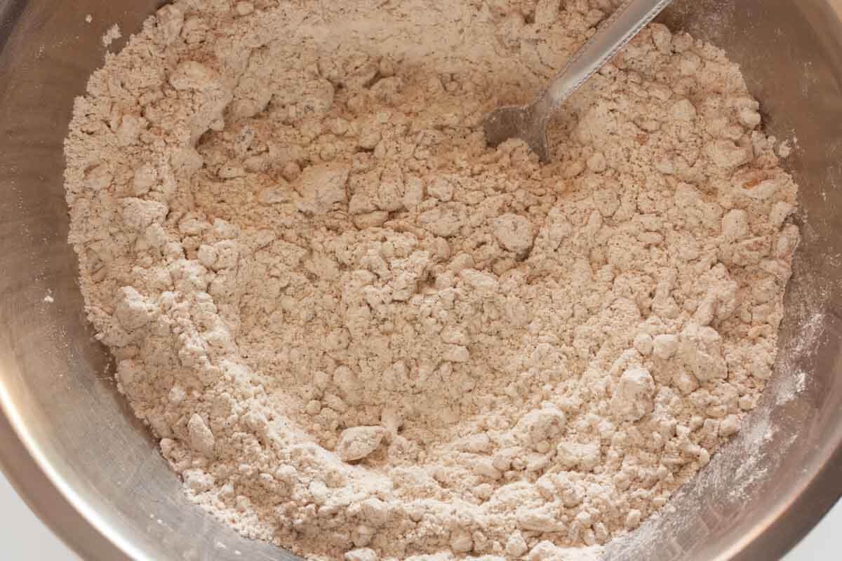 Stirring flour, spices,baking soda, baking powder, and walnuts in a large mixing bowl with a fork.