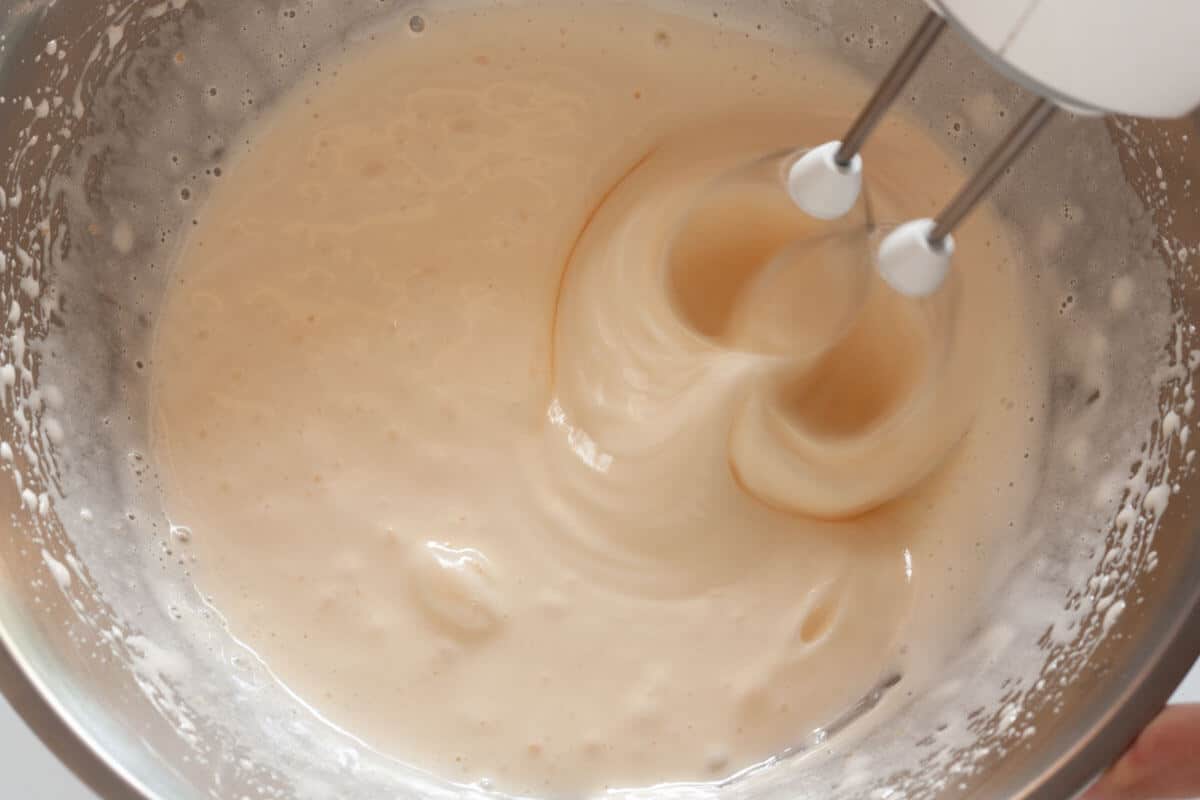 Beating eggs and sugar together in a large mixing bowl with a hand mixer.