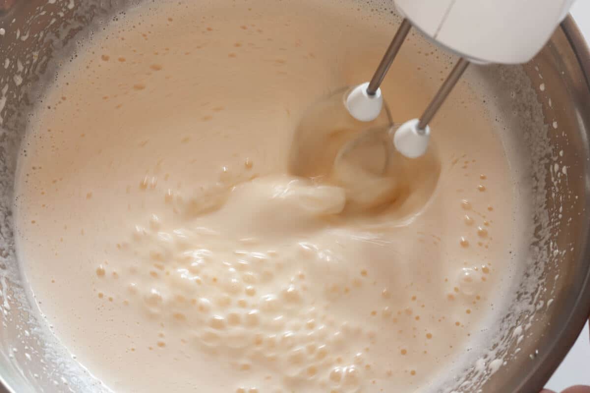 Beating milk and oil with eggs and sugar in a large mixing bowl with a hand mixer.
