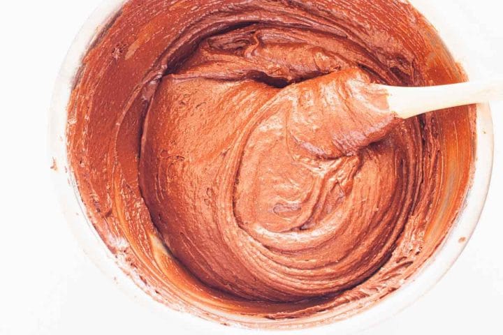 Stirring brownie batter with a silicone spatula in a metal bowl.