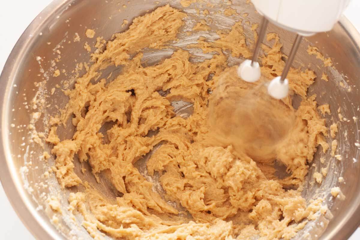 Beating vanilla and an egg in butter and sugar mixture with a hand mixer.