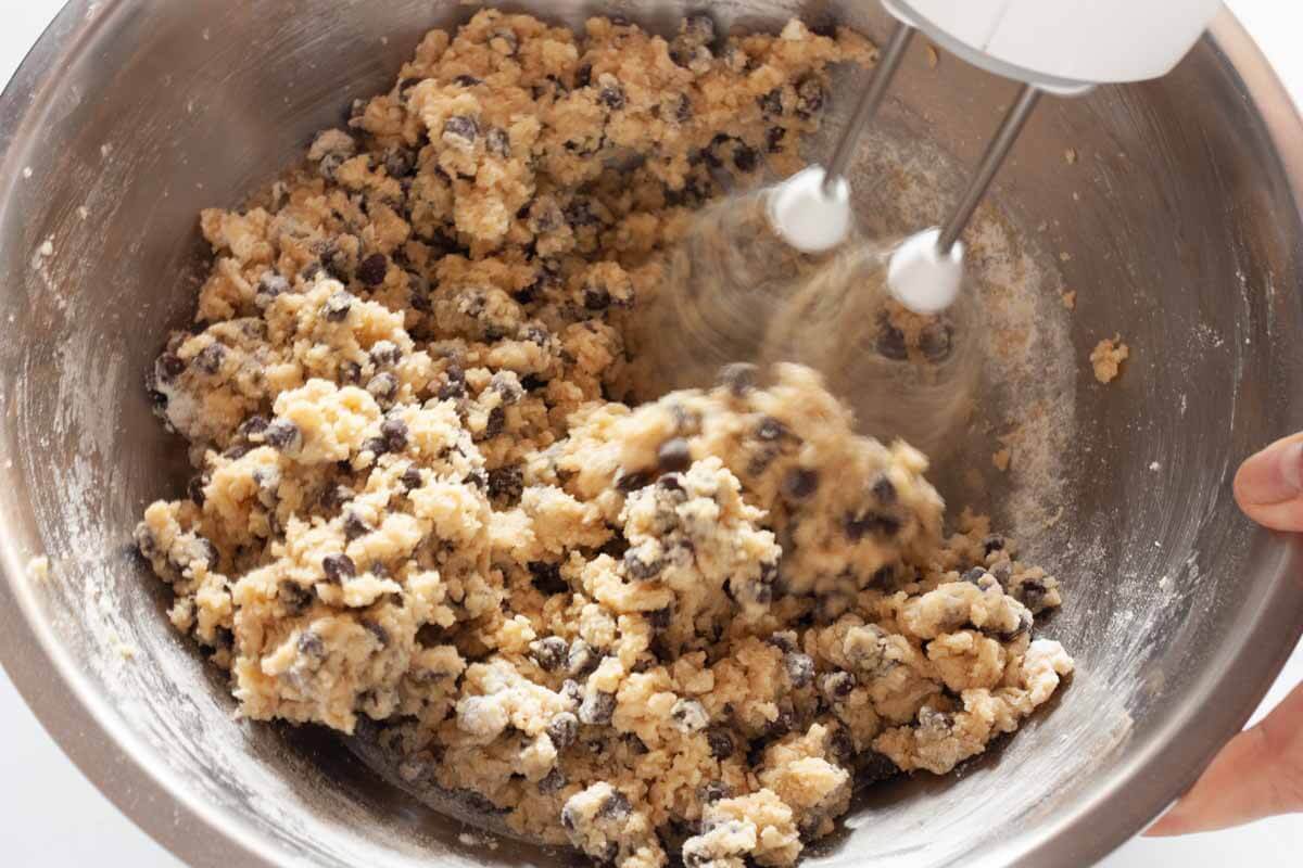 Beating dry ingredients and chocolate chips with the butter mixture with a hand mixer.