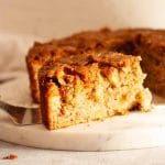 A close up of a slice of oatmeal apple cake on a white marble platter.
