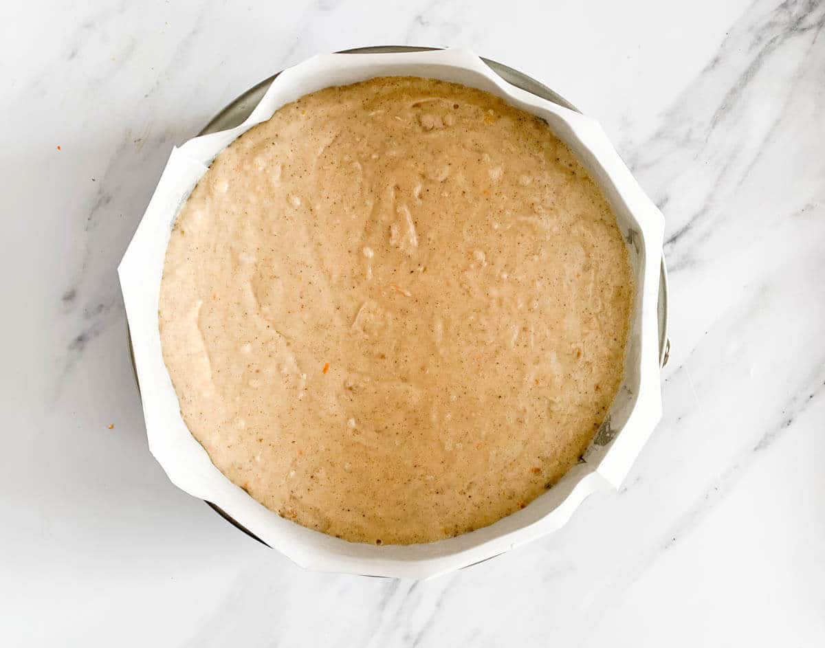 Vasilopita cake batter in a cake pan lined with parchment paper before baking.