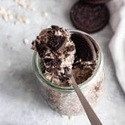 An overhead shot of Oreo overnight oats with crushed Oreo cookies on a spoon next to Oreo cookies and oats.