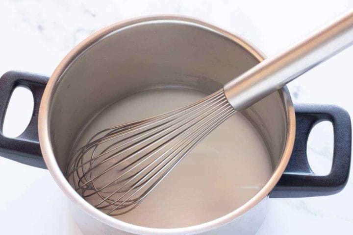 Cornstarch mixed with water in a saucepan with a whisk.