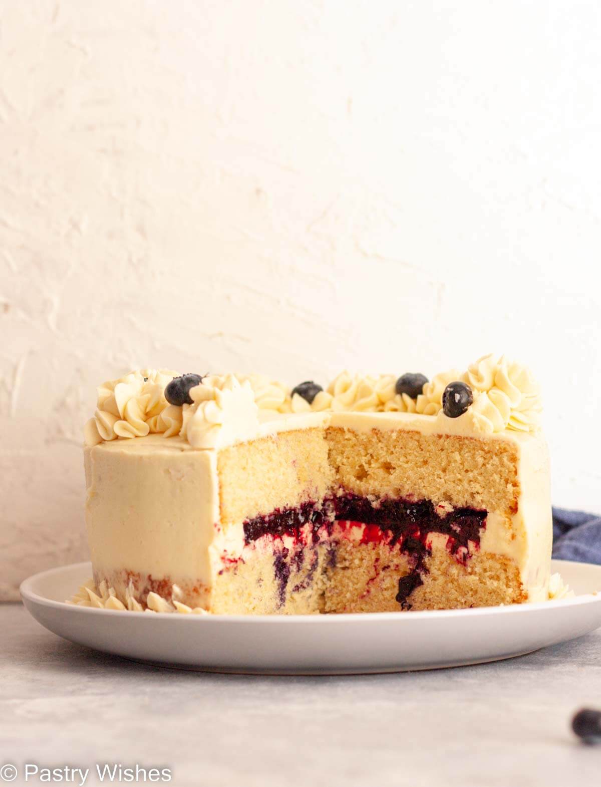 A two-layer vanilla cake with blueberry filling on a white plate.