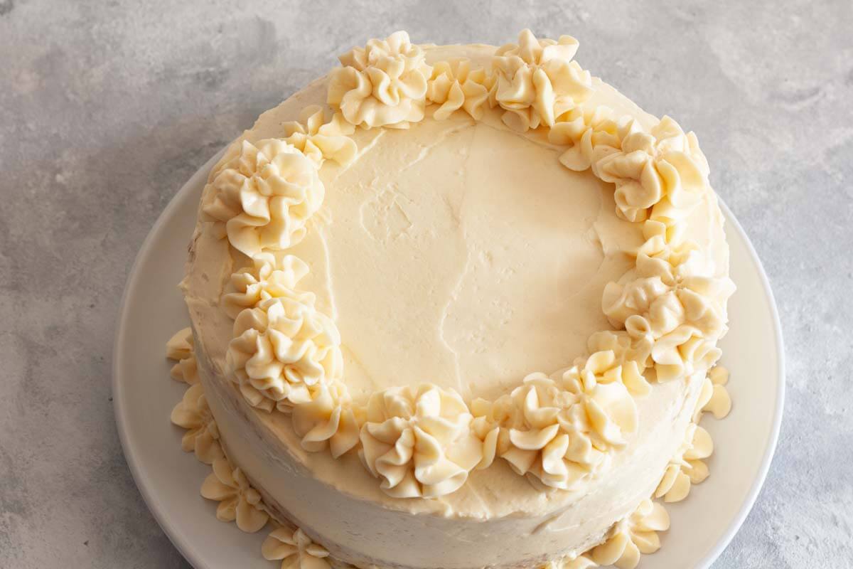 Swirls on top of a frosted two-layer vanilla cake with vanilla buttercream.