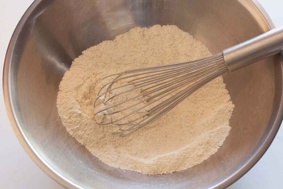 Whisking flour, almond flour, baking powder and salt in a metal bowl.