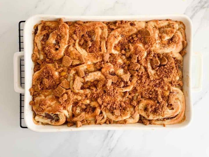 Crushed Biscoff cookies over baked peach cinnamon rolls.
