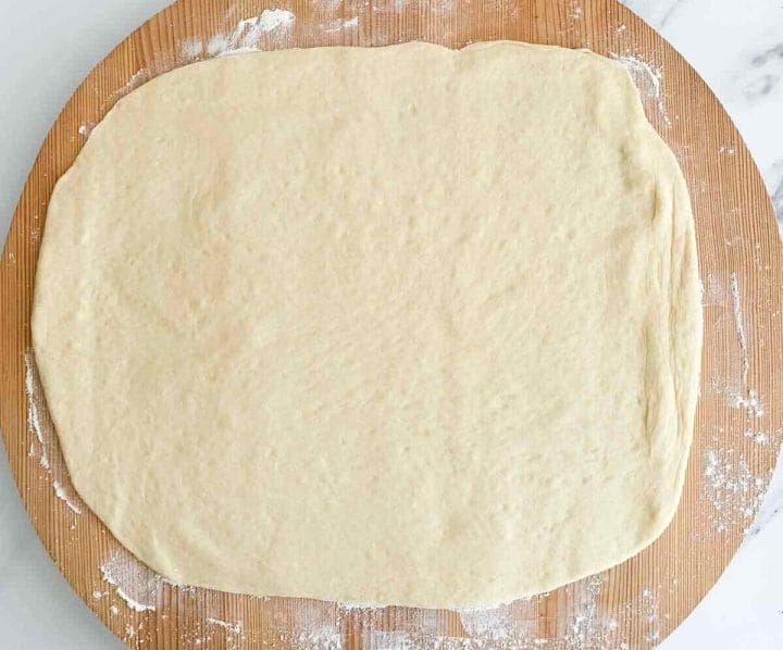 Rolled out dough in a rectangle on a floured wooden surface.