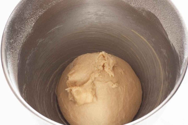 Fully kneaded dough in a metal bowl of a stand mixer.