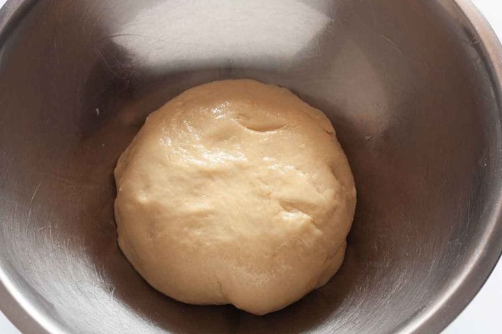 Kneaded dough in a greased metal bowl before it has risen.