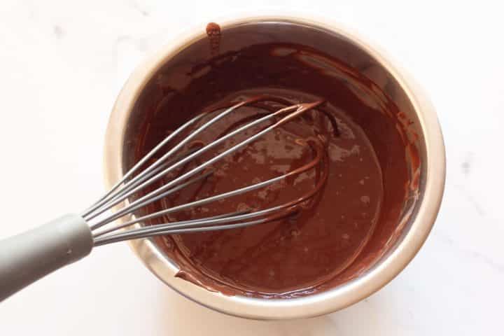 Whisking cocoa powder and boiling water in a metal bowl.