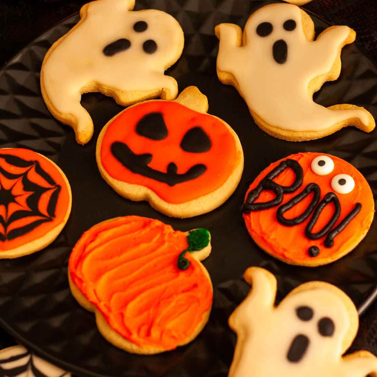 Halloween cut out cookies on a black plate.