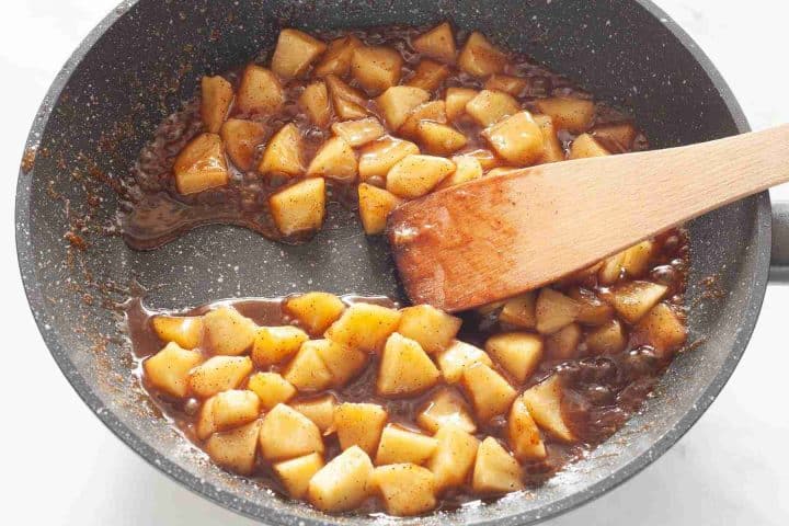 Cooked and thickened apple filling in a large skillet.