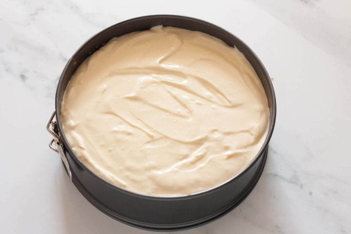 Cheesecake filling over crust in a springform pan.