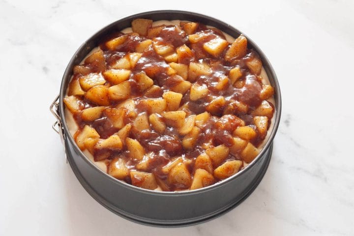 Cooled apple filling over cheesecake filling in a springform pan.