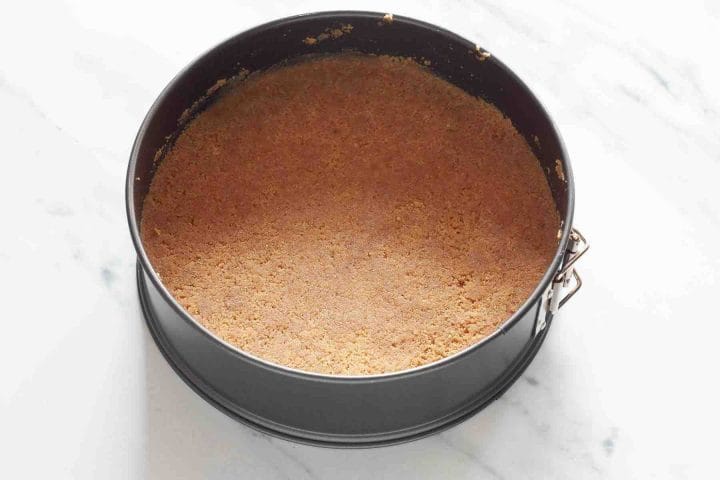 Cheesecake crust in a springform pan before baking.