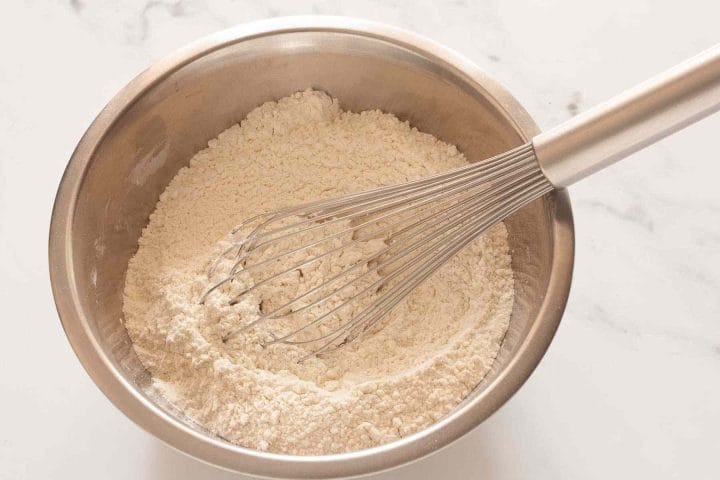 Whisking dry ingredients in a metal mixing bowl.