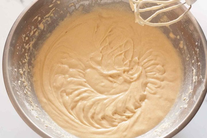 Fully combined vanilla cake batter in a metal mixing bowl.
