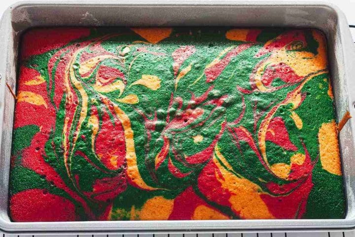 A baked Christmas sheet cake in a baking pan on a wire rack.