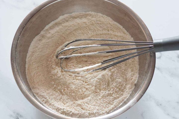 Whisking dry ingredients in a metal mixing bowl.