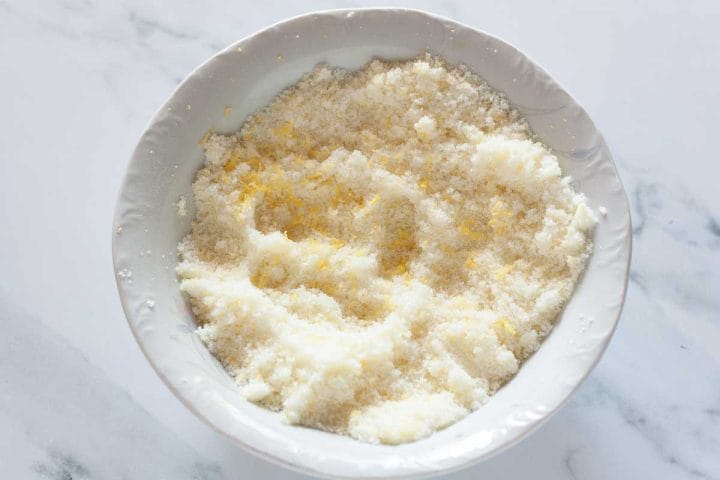 Lemon zest mixed with granulated sugar in a white bowl.