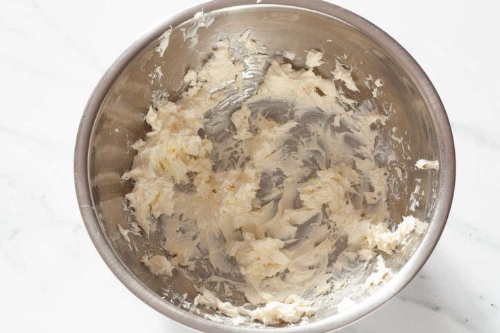 Softened cream cheese in a metal bow.