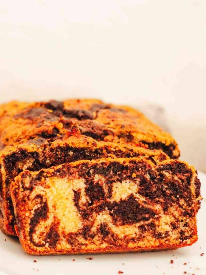 A close up of sliced marble loaf cake on a white plate.