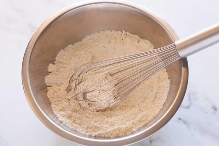 Whisking dry ingredients in a metal bowl with a whisk.