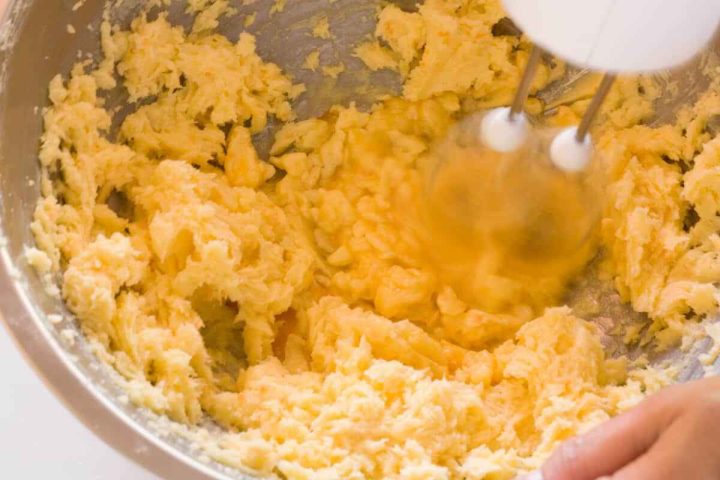 Adding eggs to the koulourakia cookie dough mixture.