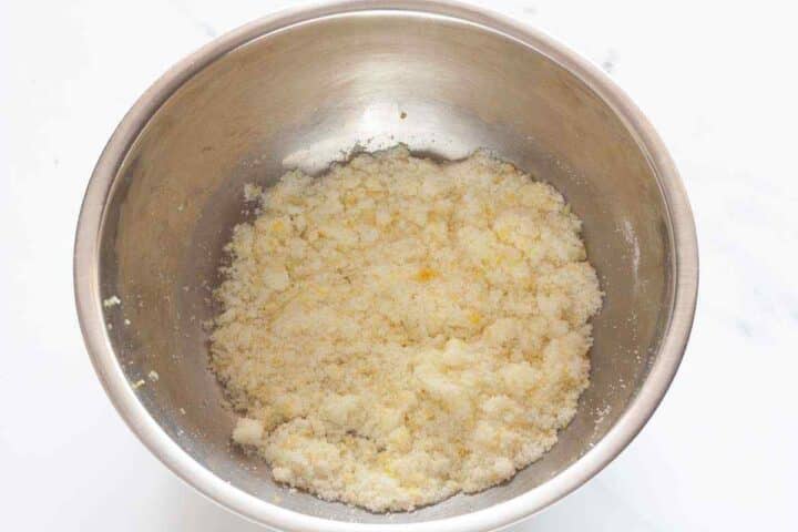 Lemon zest mixed into granulated sugar for lemon raspberry loaf cake.