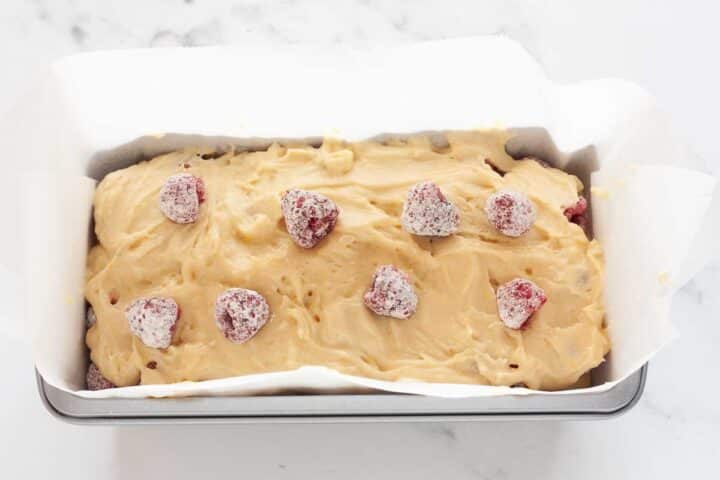 Raspberries topped over batter in lemon raspberry loaf cake.