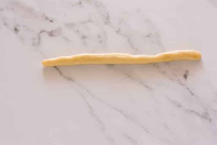 Rolling dough rope to shape traditional koulourakia cookies.