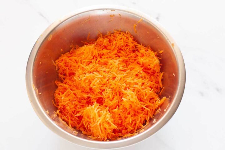 Freshly grated carrots in a metal bowl.