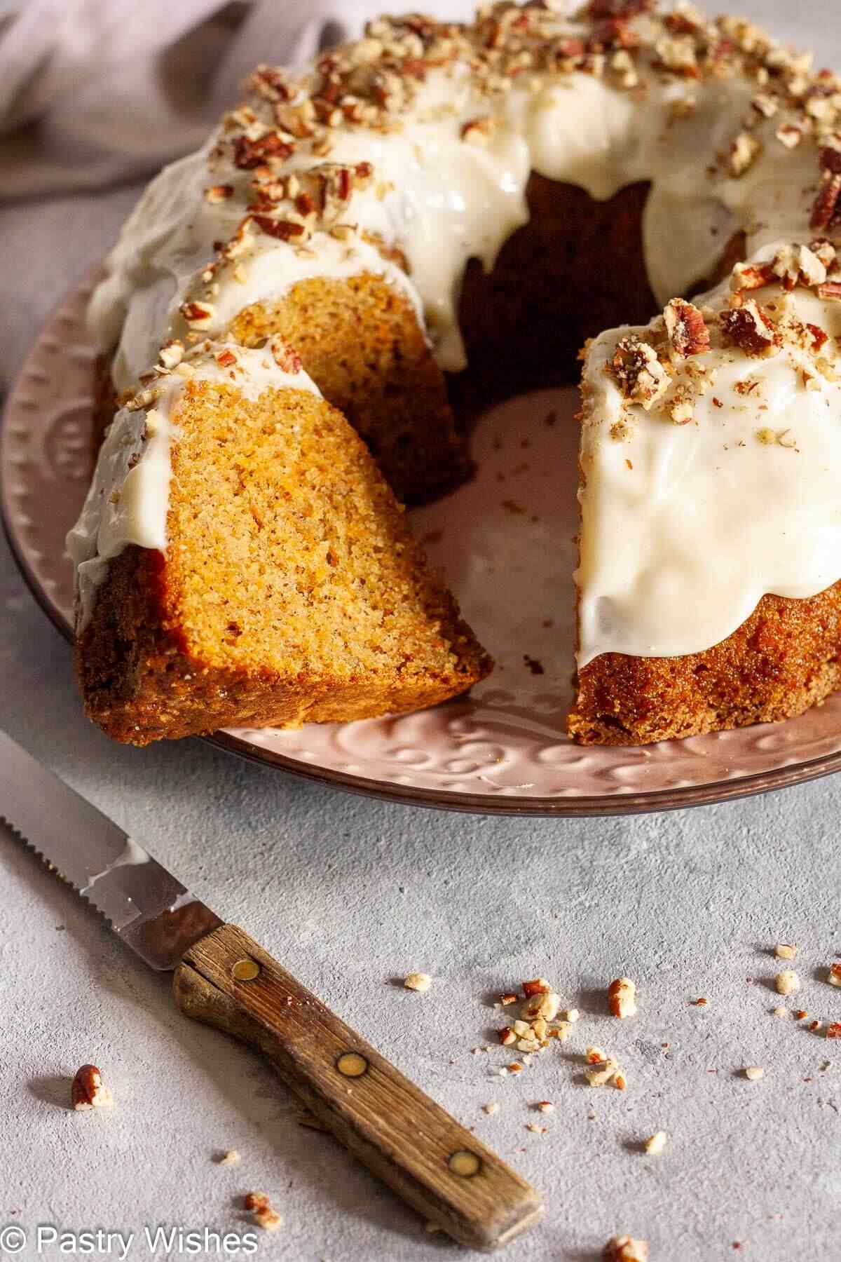 Sliced carrot Bundt cake on a pink plate next to a knife.