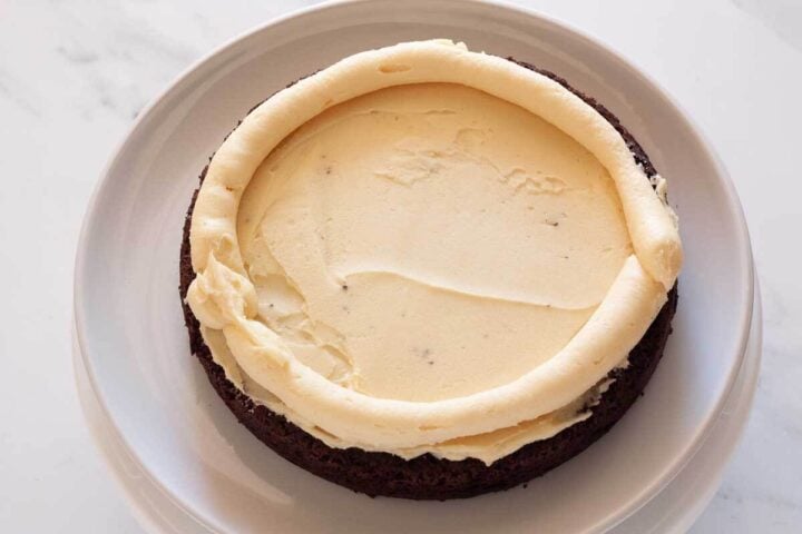 Chocolate cake layer with vanilla buttercream spread and piped buttercream border.