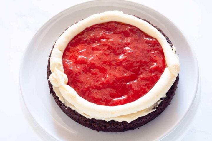 Chocolate cake layer with vanilla buttercream and strawberry filling inside a piped buttercream border.