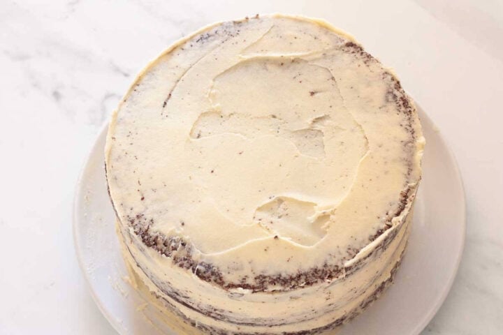 Chocolate strawberry layer cake with a thin crumb coat of vanilla buttercream.