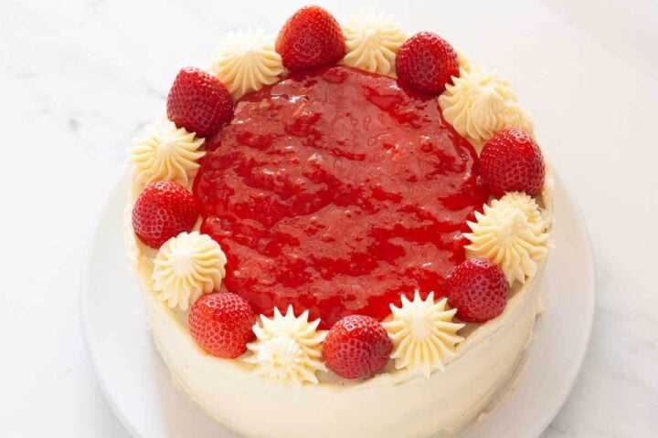 Chocolate cake with strawberry filling and vanilla buttercream frosting topped with fresh strawberries.