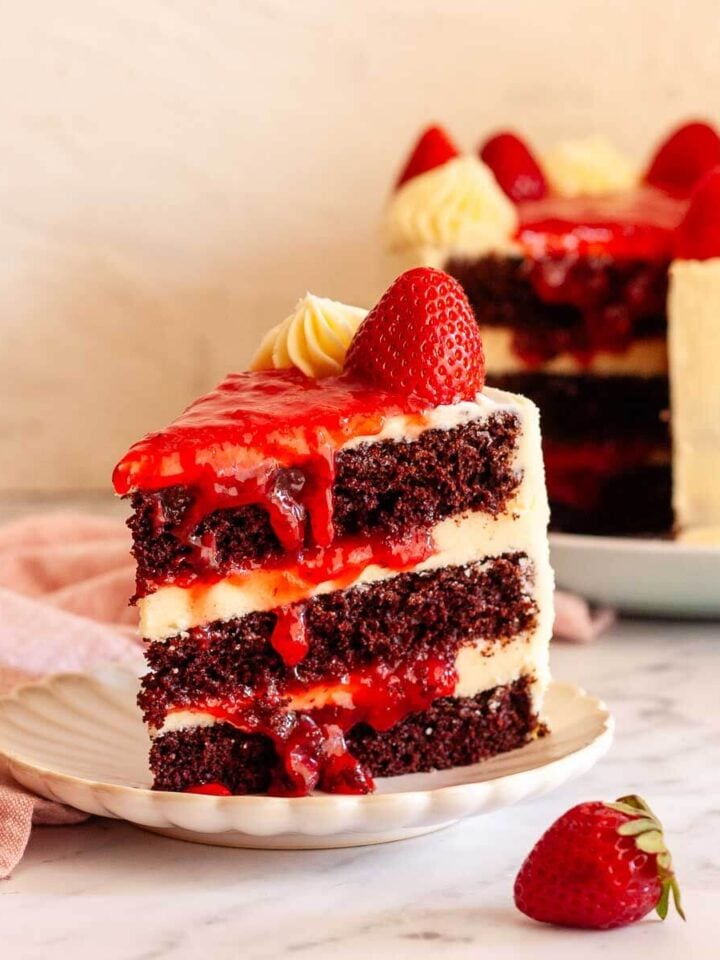 Slice of chocolate cake with strawberry filling and vanilla buttercream frosting.